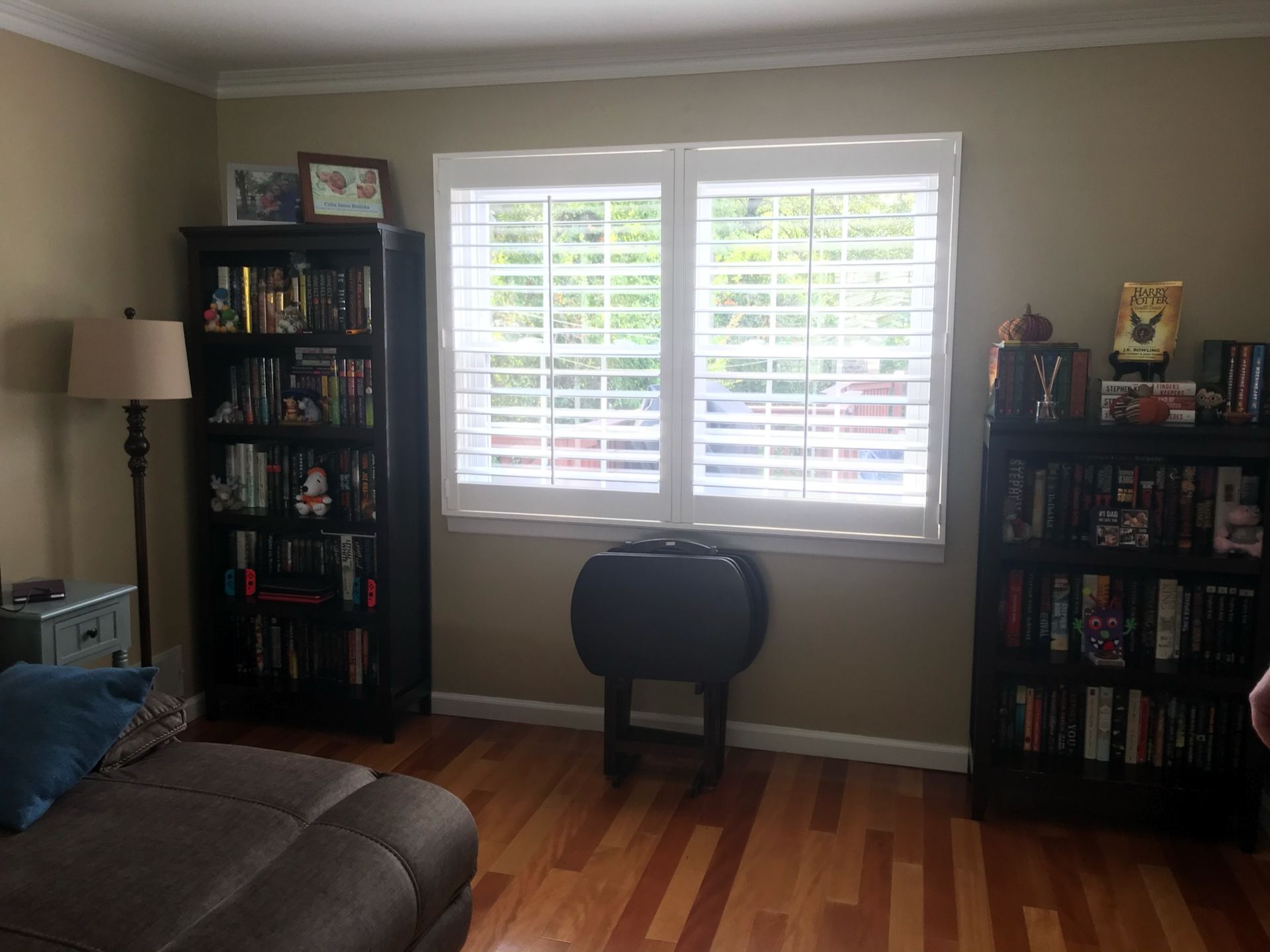 Living room with bookshelves, window with shutters, and a drop-leaf table.