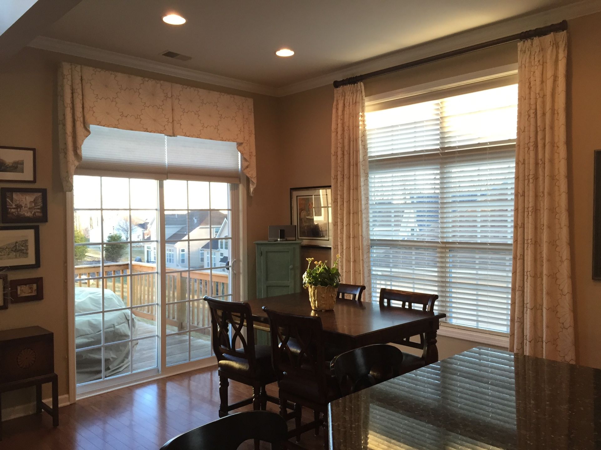 Dining room with a table, chairs, windows, and patterned curtains.