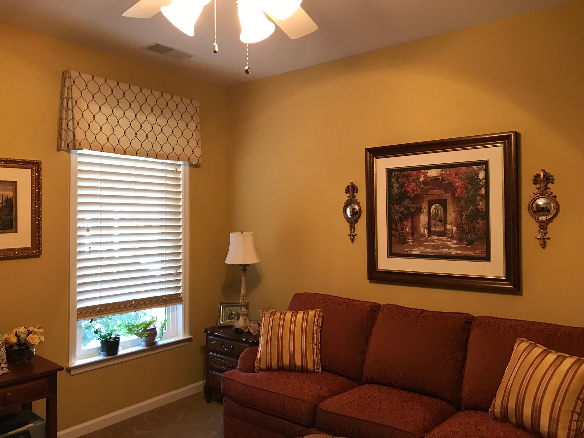 Room with a brown couch, painting, blinds, and yellow walls.