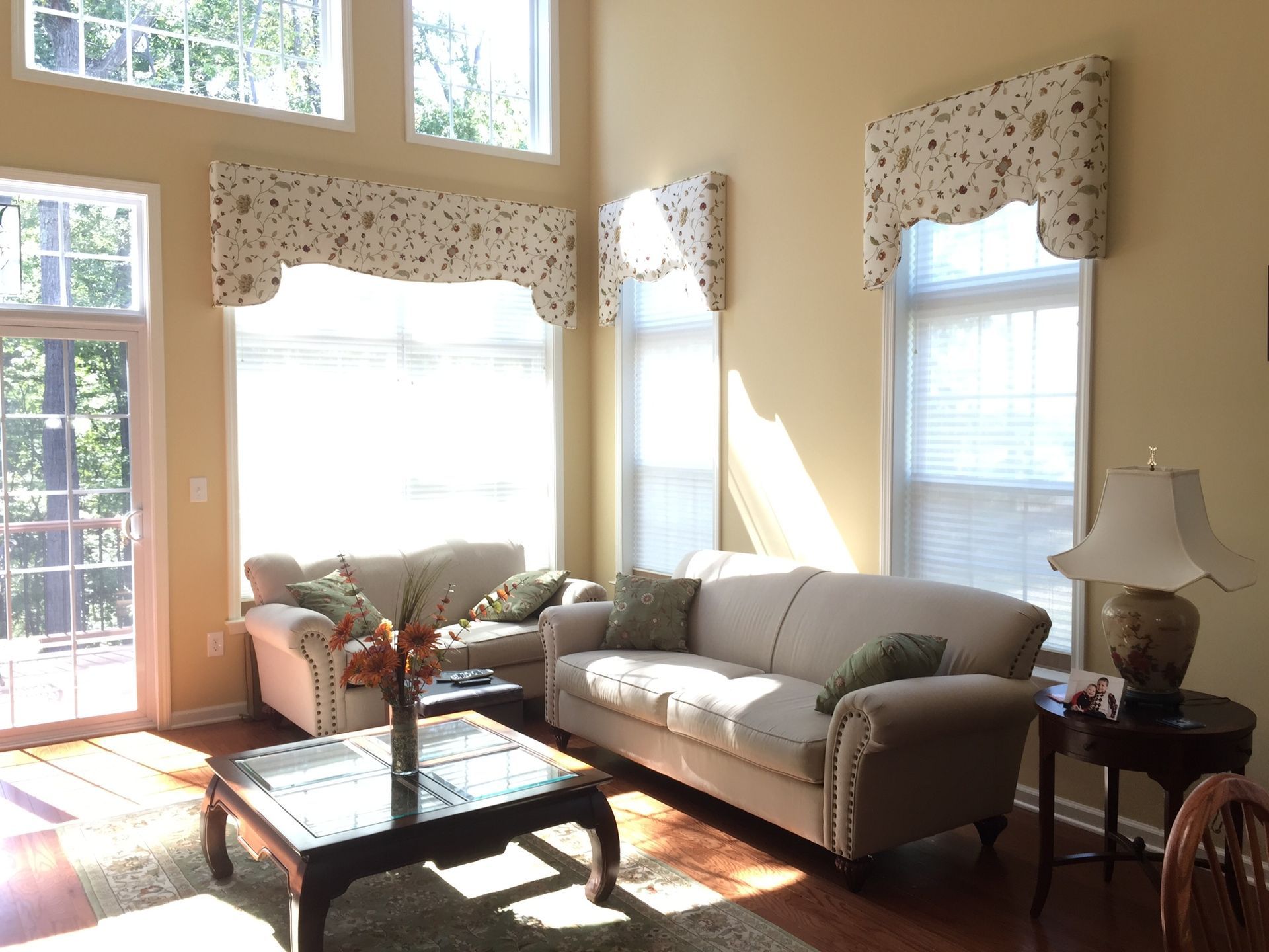 Living room with two sofas, coffee table, side table, and decorative window valances.