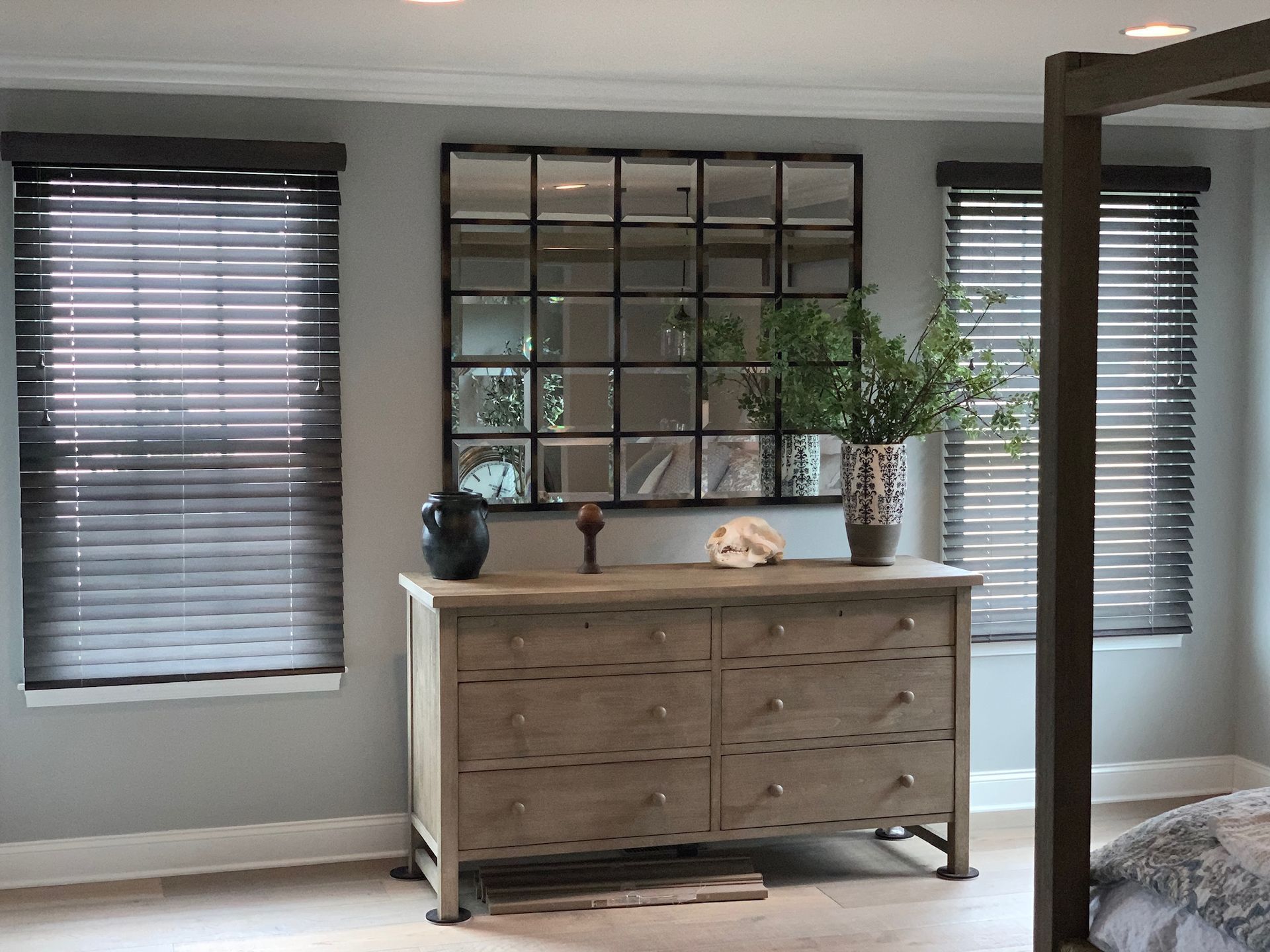 Bedroom with dresser, large window mirror, and blinds. Gray walls, wooden furniture.