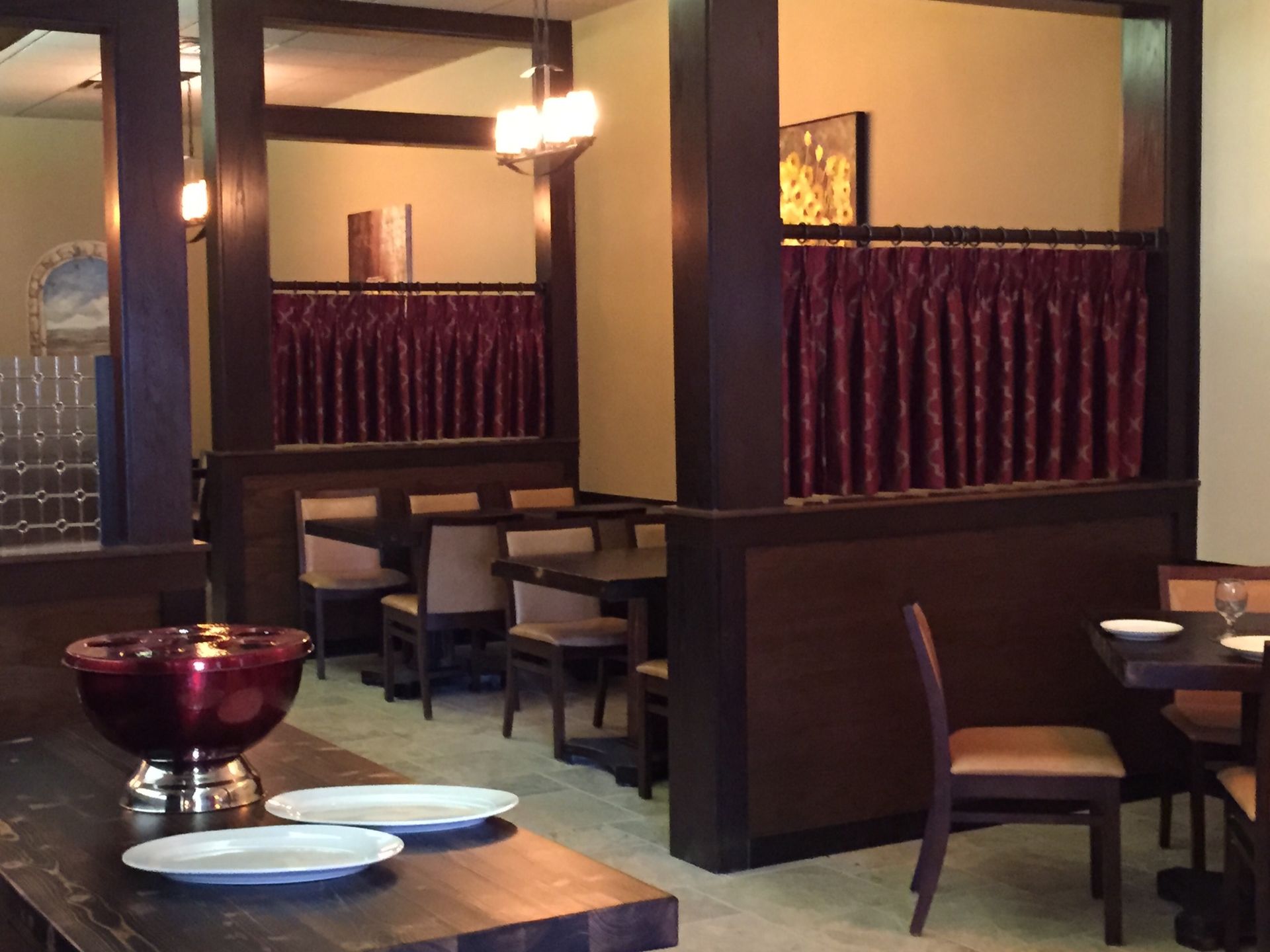 Restaurant interior: Dark wood booths, red curtains, tables set for dining.
