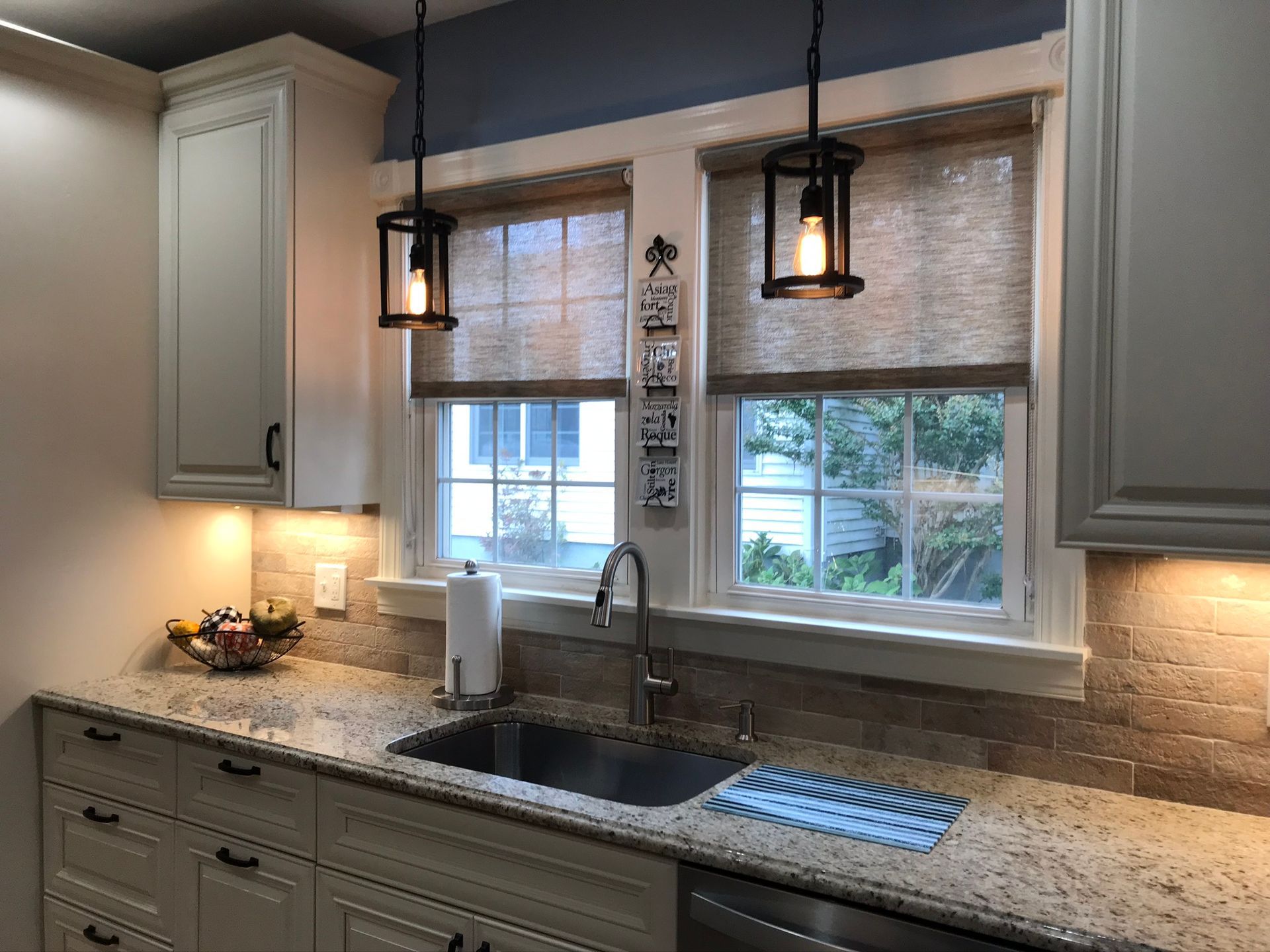 Kitchen with granite countertops, sink, windows with shades, and pendant lights.