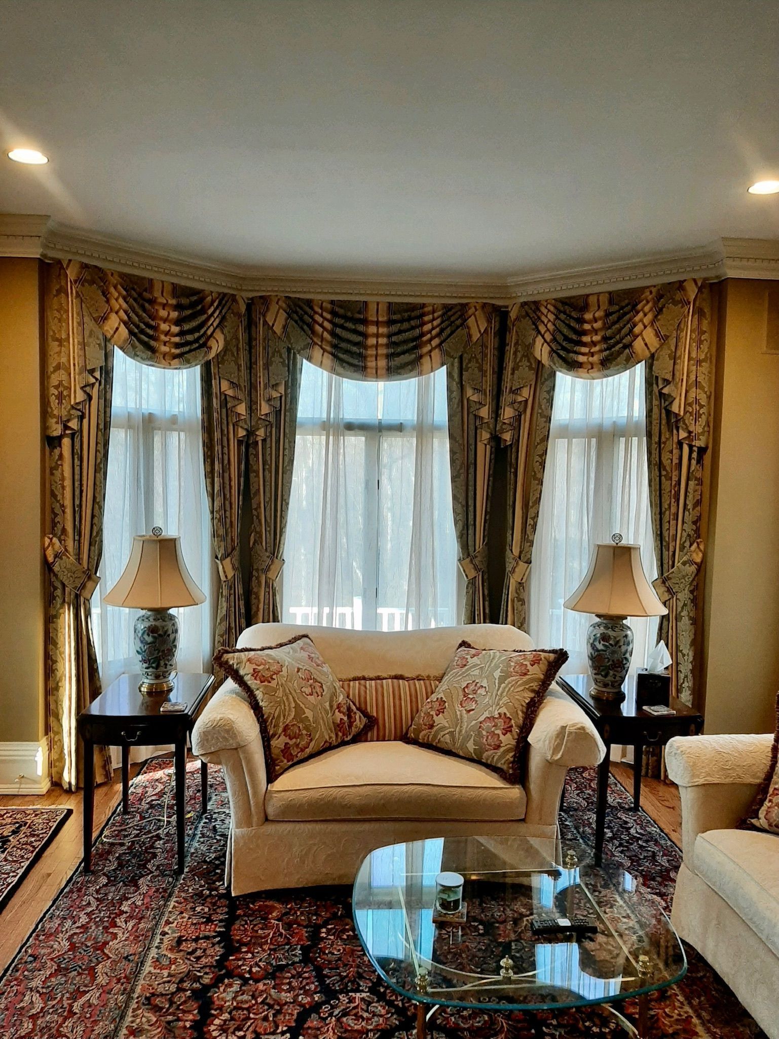 Living room with a white couch, bay window with curtains, and rug.