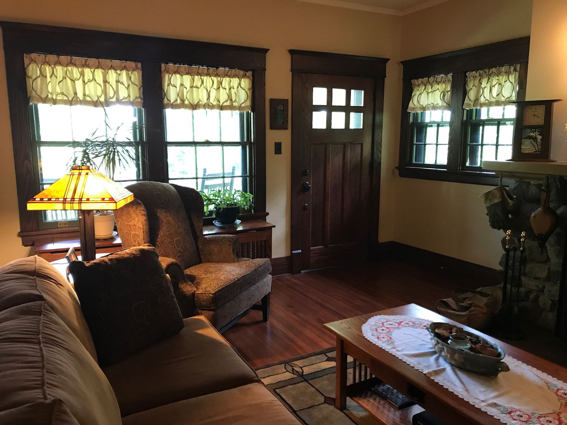 Cozy living room with brown trim, wood floors, a fireplace, and an upholstered chair and sofa.