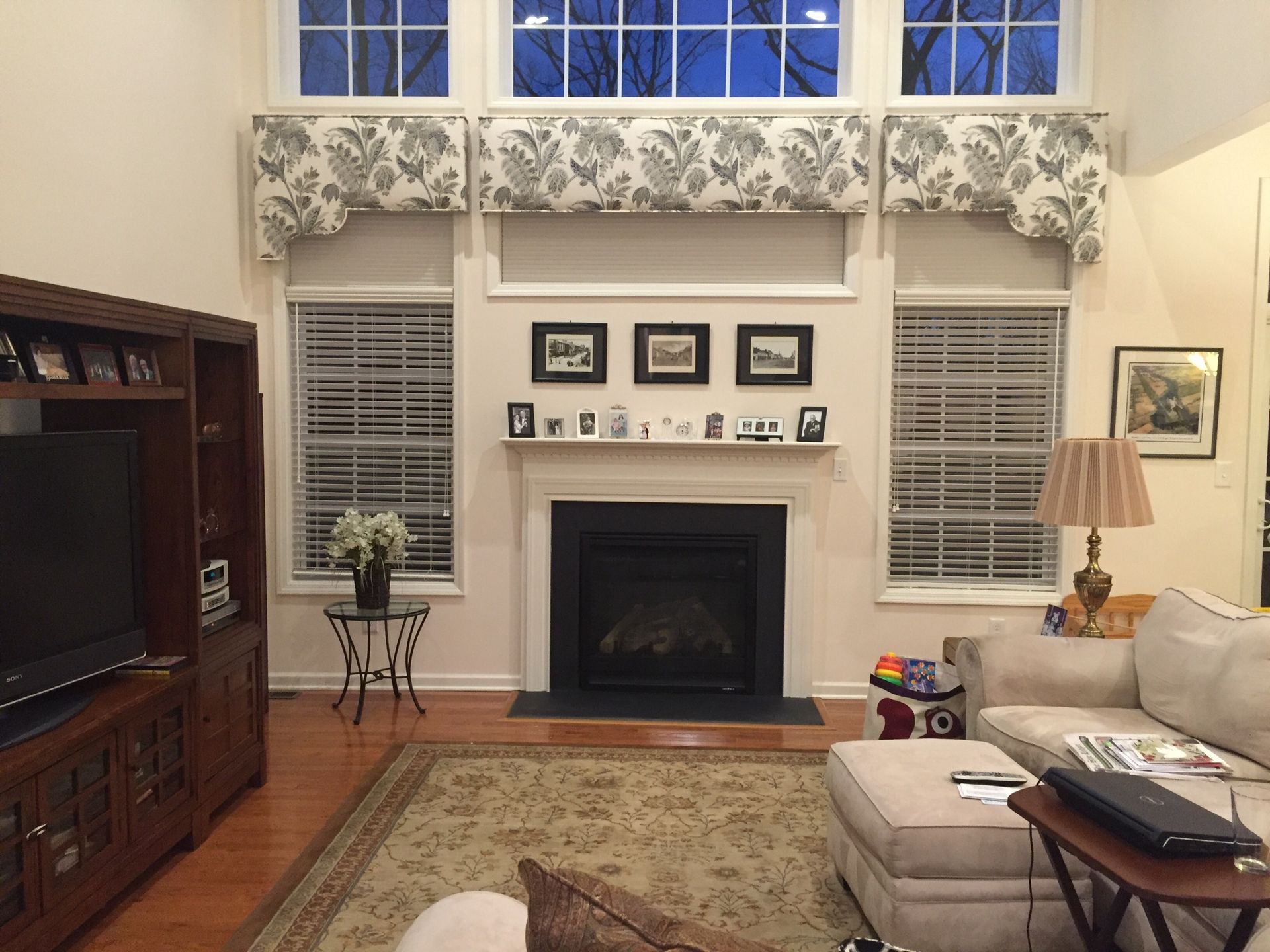 Living room with a fireplace, TV, and floral window valances.