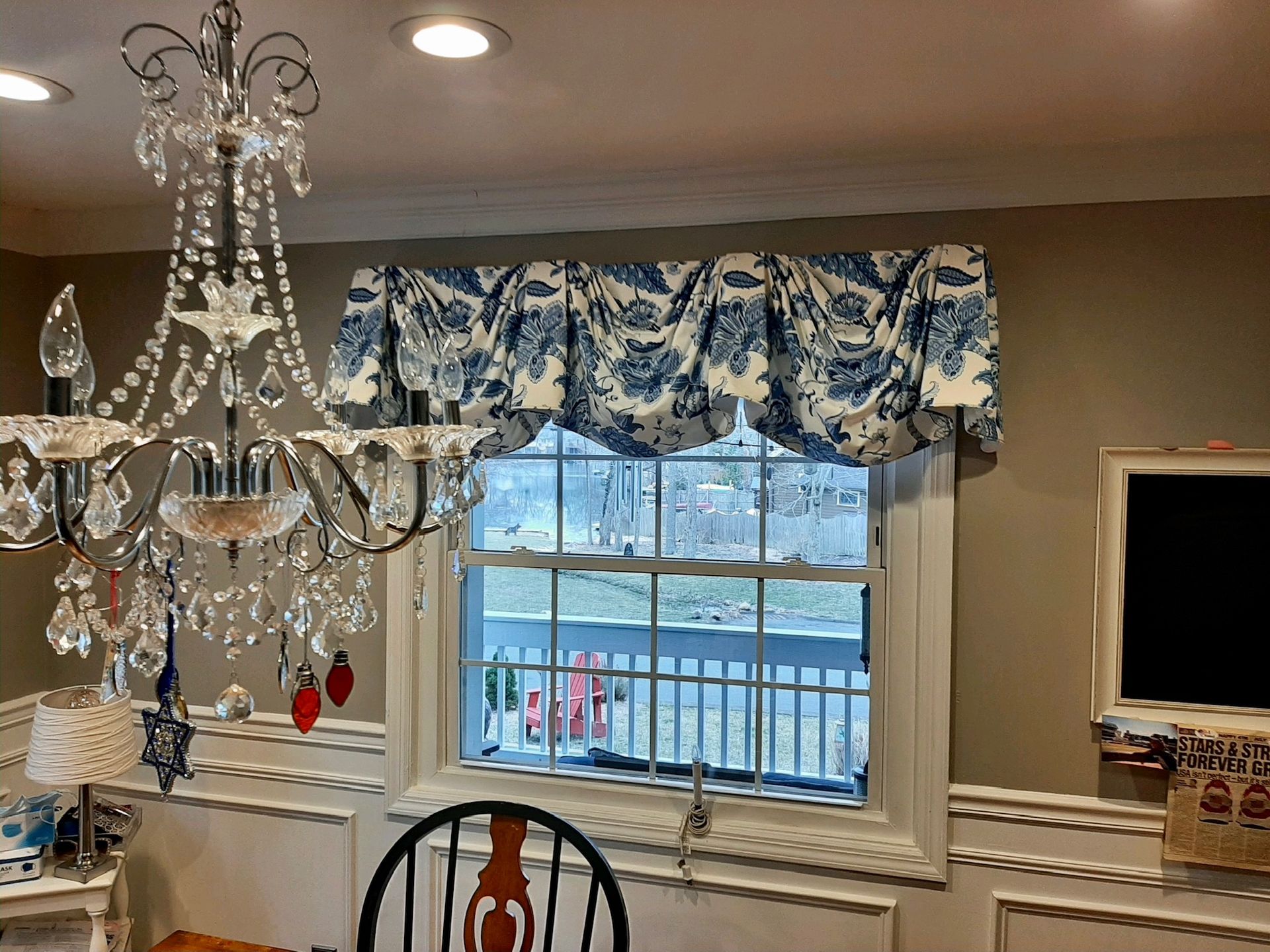 Window with blue and white valance and a chandelier.