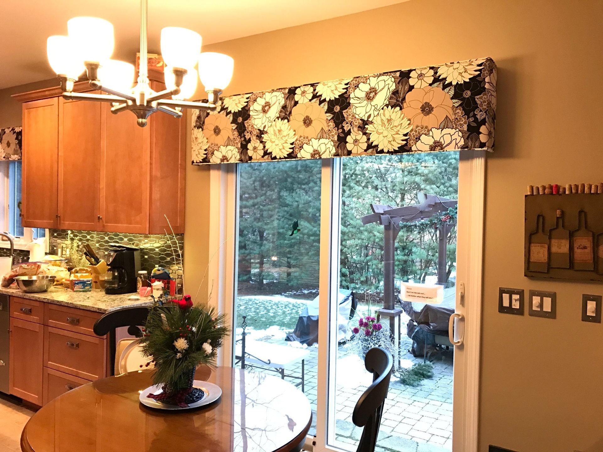 Kitchen with floral valance over a sliding glass door and a round dining table.