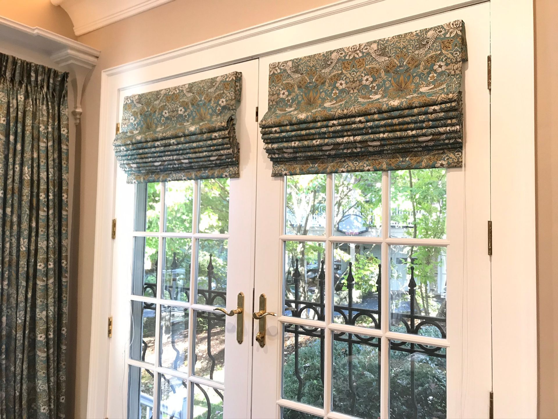 French doors with patterned Roman shades; outdoors visible.