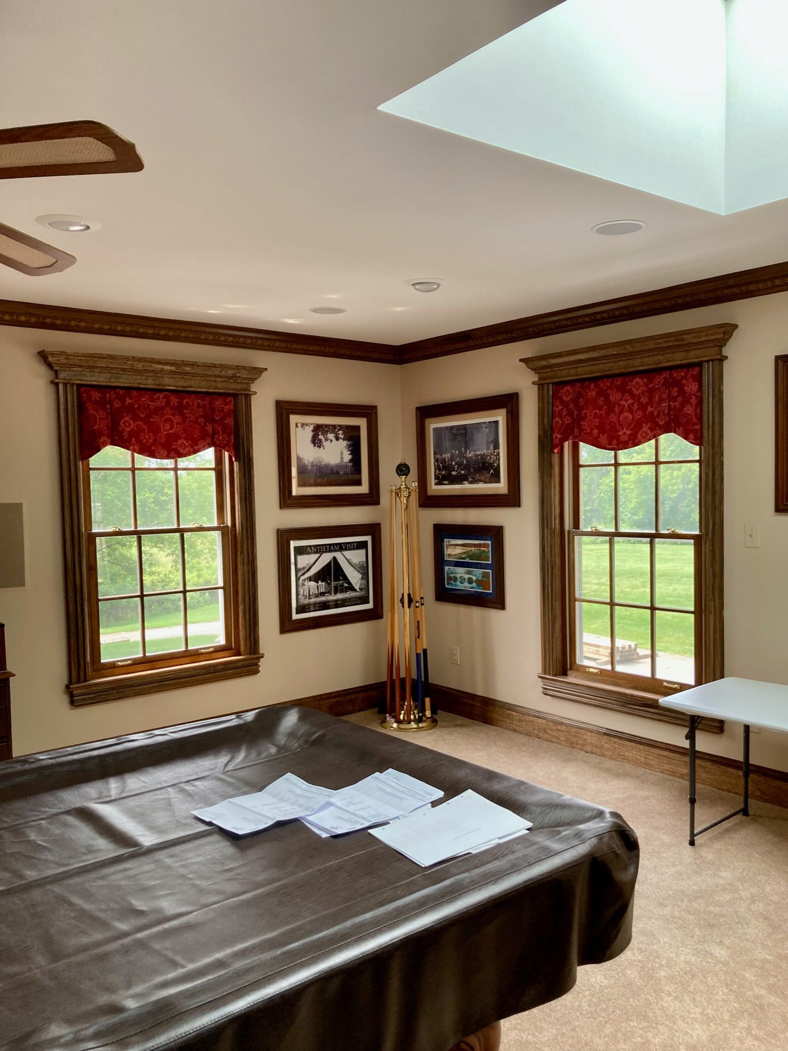Pool table with playing cards in room with windows, artwork, and red valances.