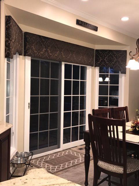 Brown patterned valances above white-framed glass doors and windows in a dining area.
