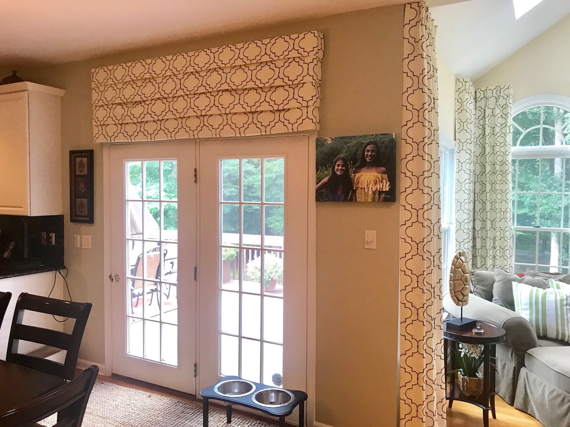 Kitchen with French doors, roman shade, artwork, beige wall, and view of living area.