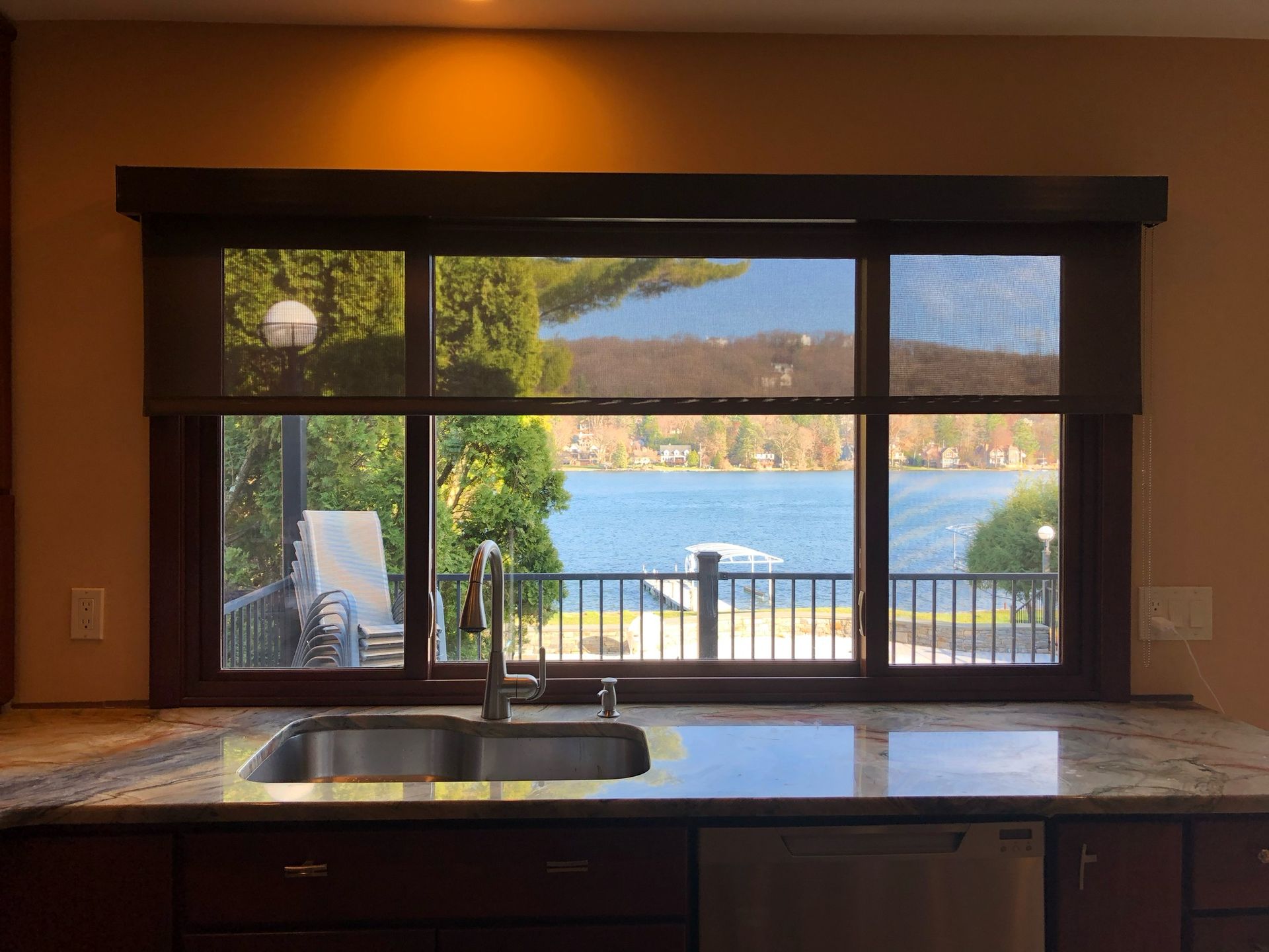 Kitchen window with a lake view; brown shades, cabinets, and a granite countertop.