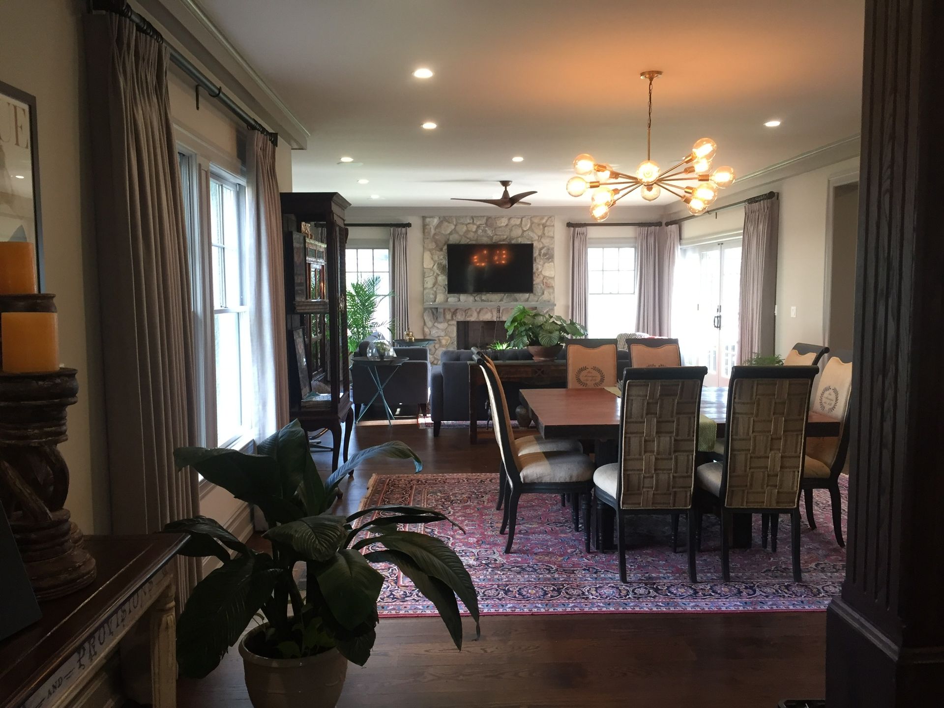 Dining room with table and chairs, opening to a living room with a fireplace and chandelier.