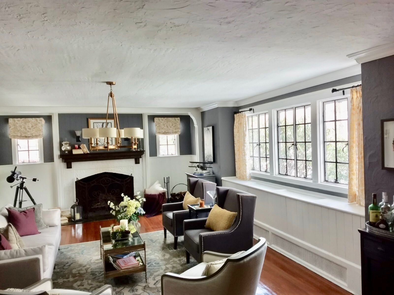 Living room with fireplace, white walls, dark gray accents, hardwood floors, and large windows.