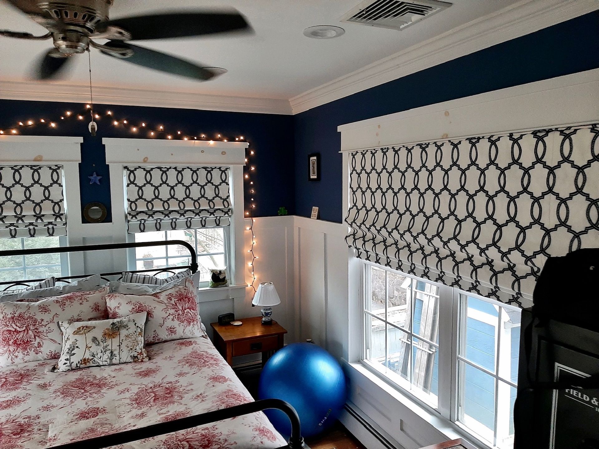 Bedroom with a bed, windows with patterned blinds, and a blue exercise ball.