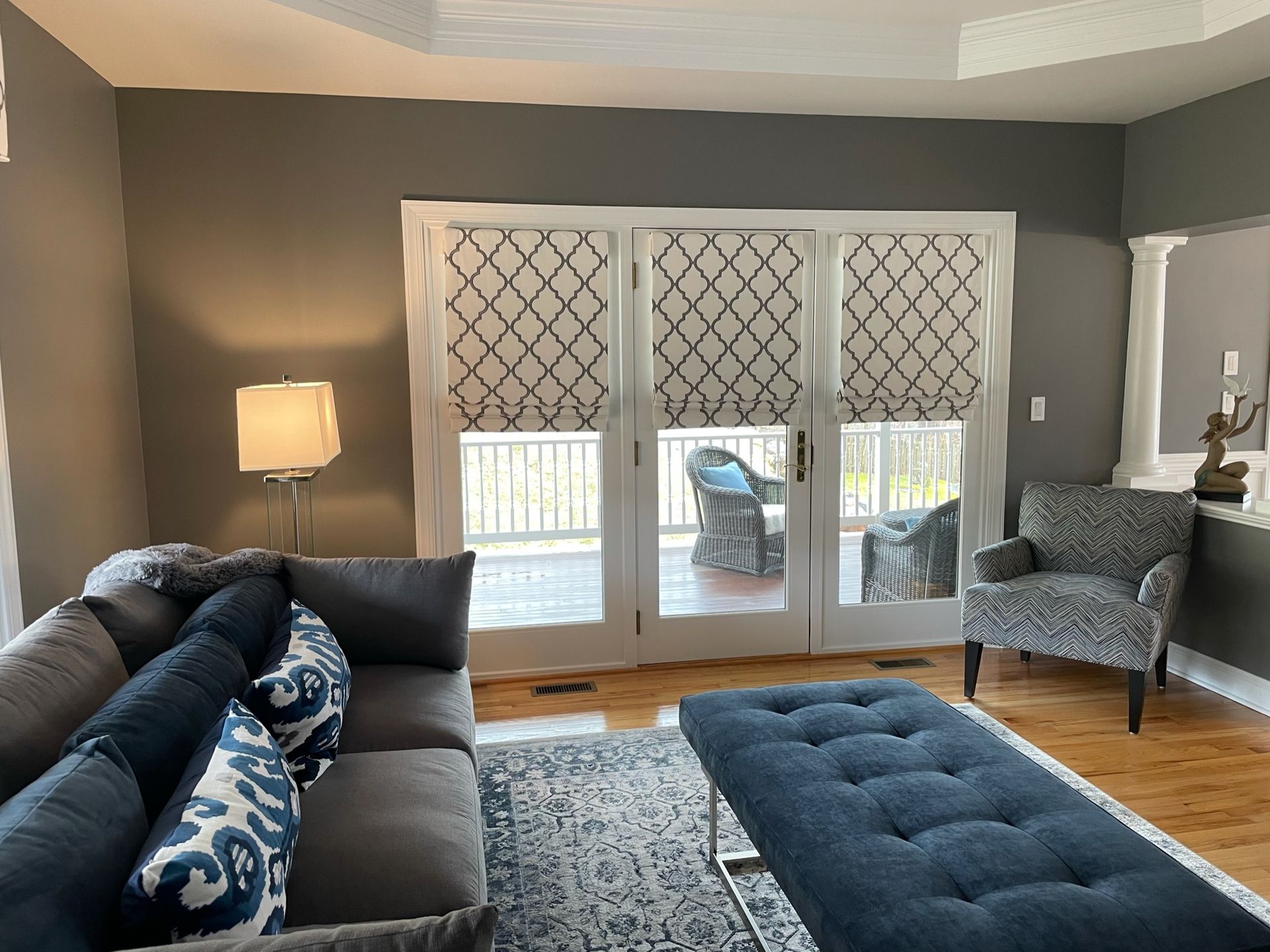 Living room with gray walls, French doors, sectional sofa, and patterned blinds.