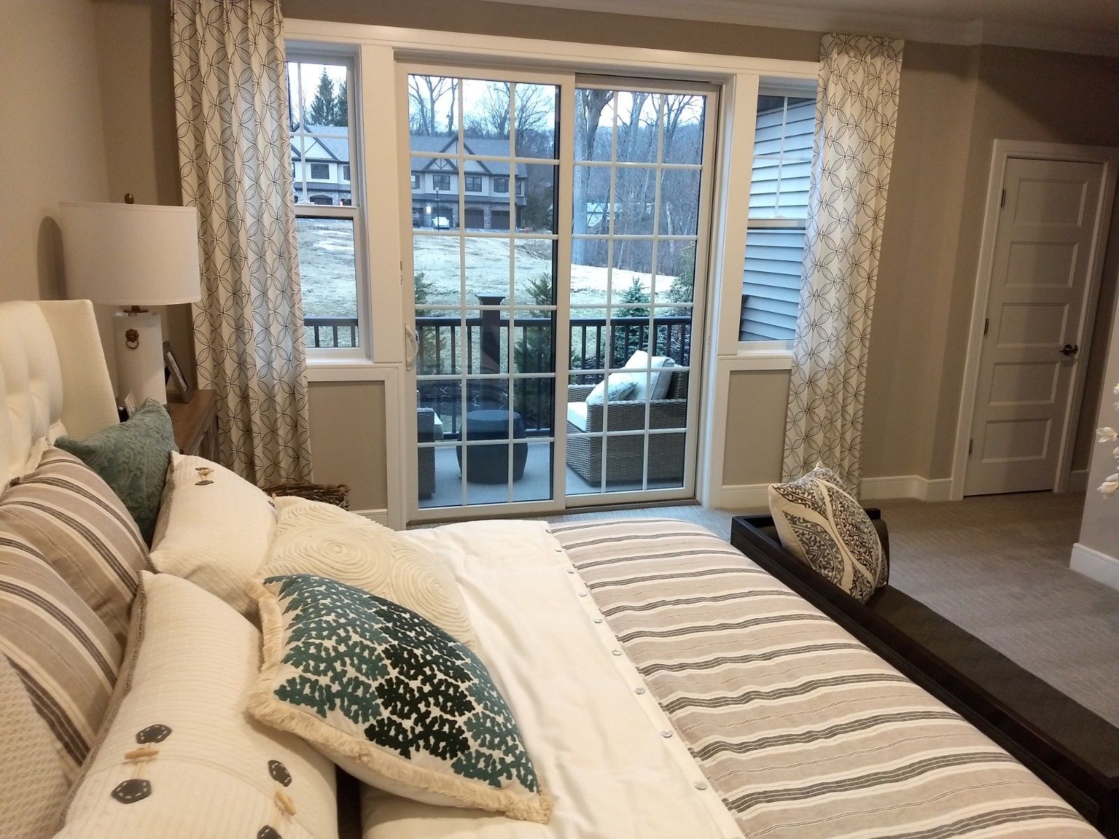 Bedroom with bed, window, and balcony overlooking a snowy scene. Light curtains frame the window.