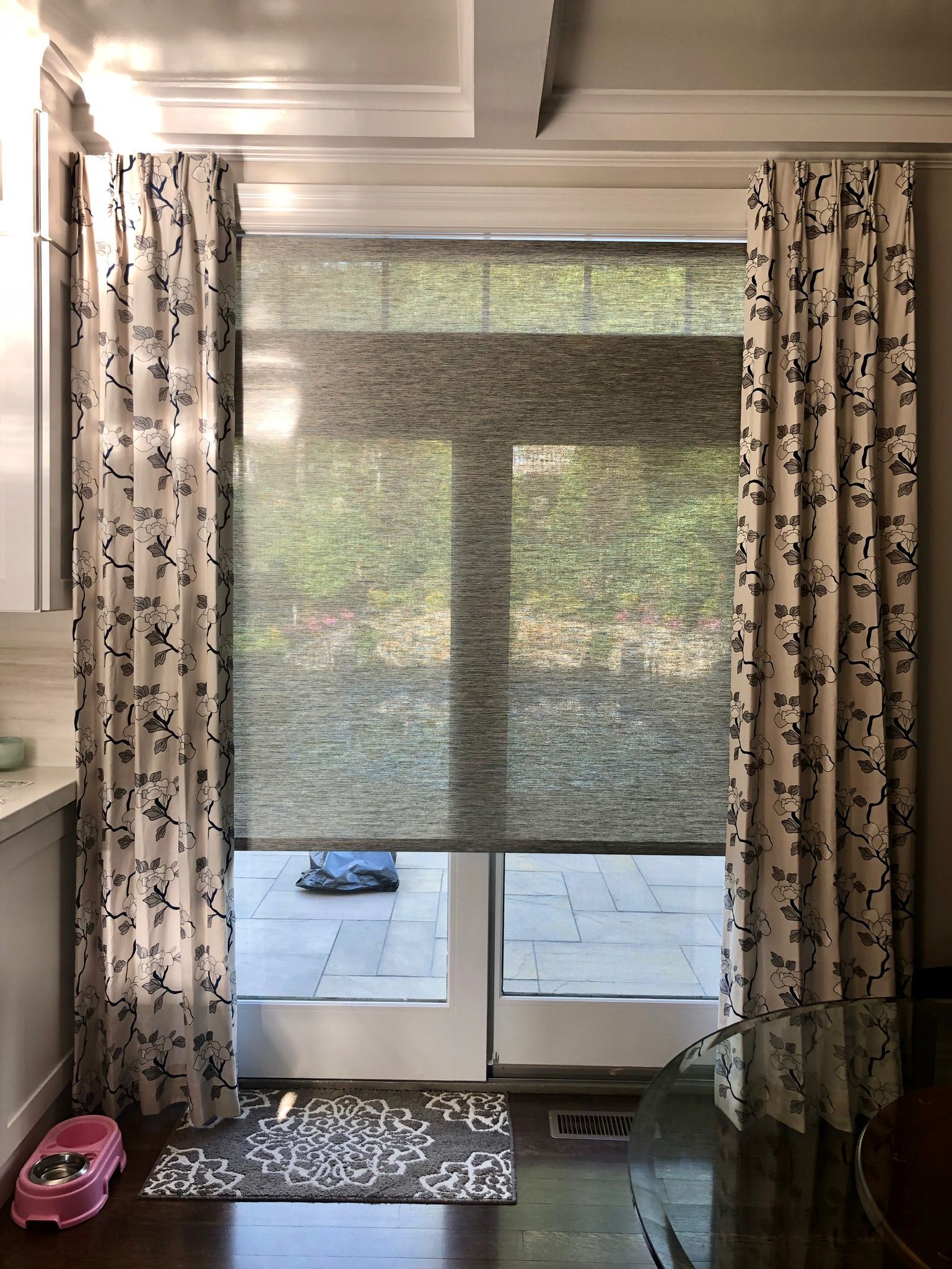 Door with patterned curtains, and a woven shade. Interior setting.
