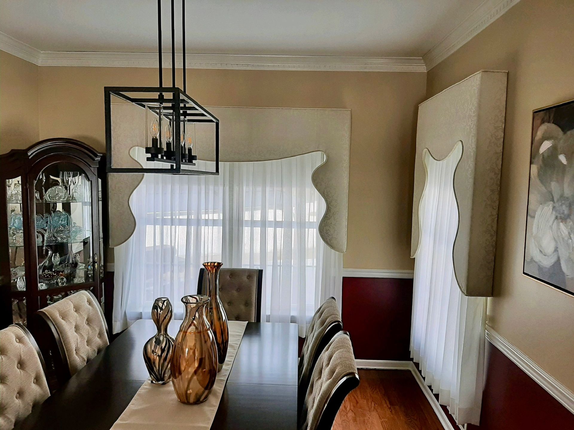 Dining room with a long table, chairs, chandelier, and a decorative dress display.