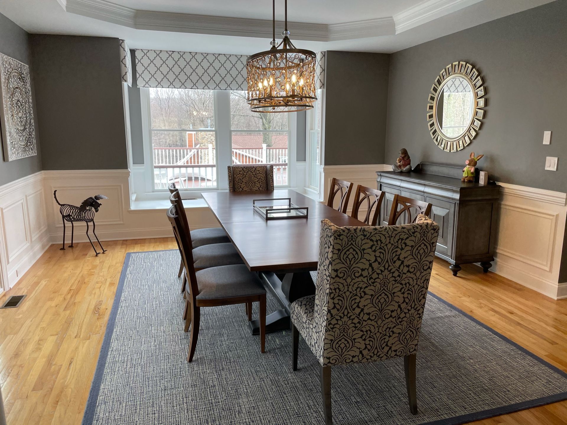 Formal dining room with dark wood table, chairs, chandelier, and gray walls.