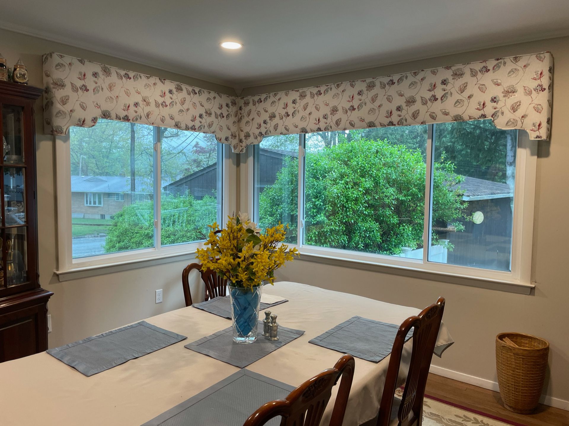 Dining room with table, floral centerpiece, windows, and floral valances.