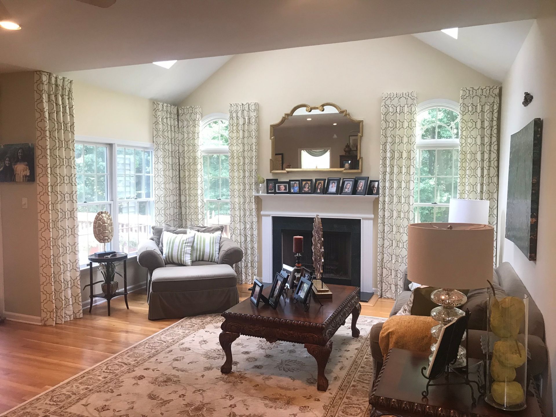 Living room with fireplace, ornate furniture, patterned curtains, and beige walls.