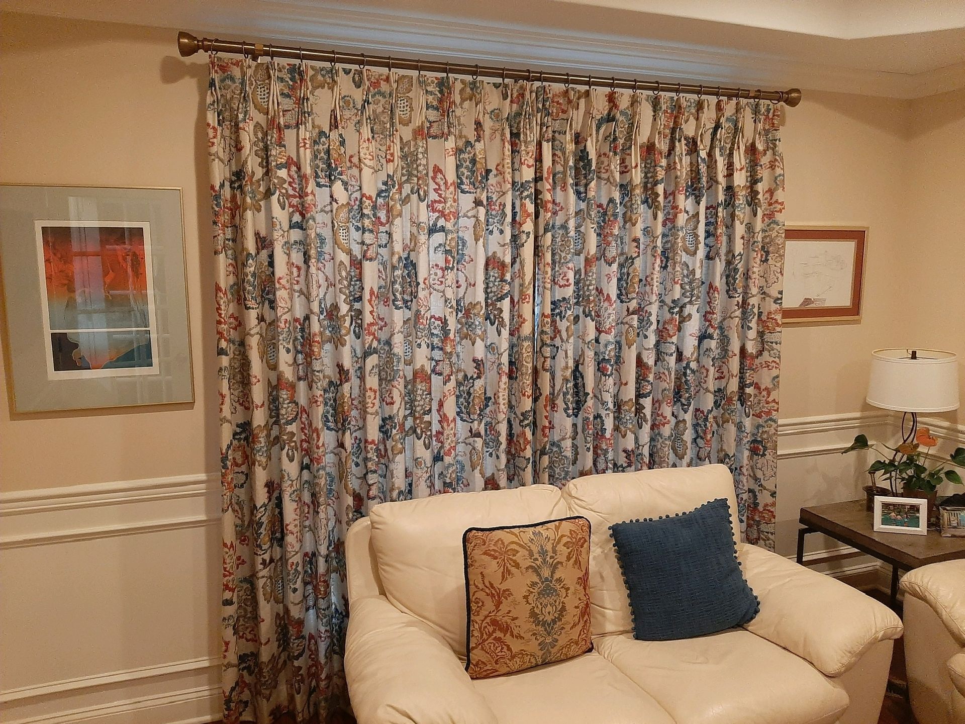 Living room with cream couch, patterned curtains, and framed art.