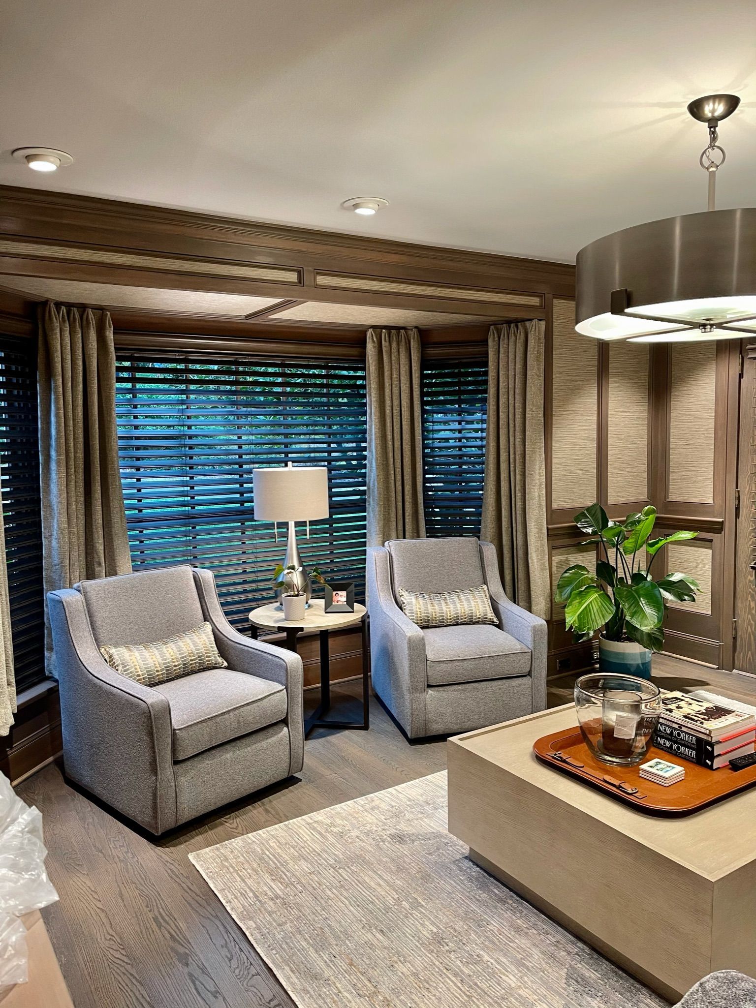 Cozy living room with gray chairs, a coffee table, and a large window with curtains.