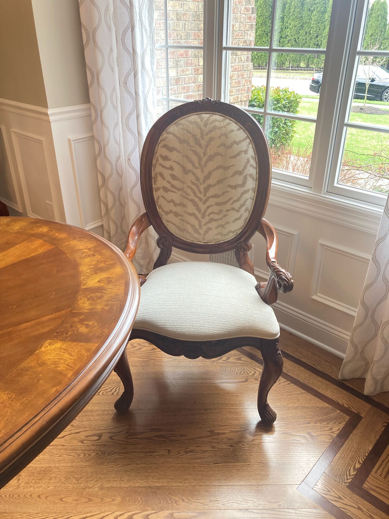 Antique chair with oval back and patterned upholstery near a window.
