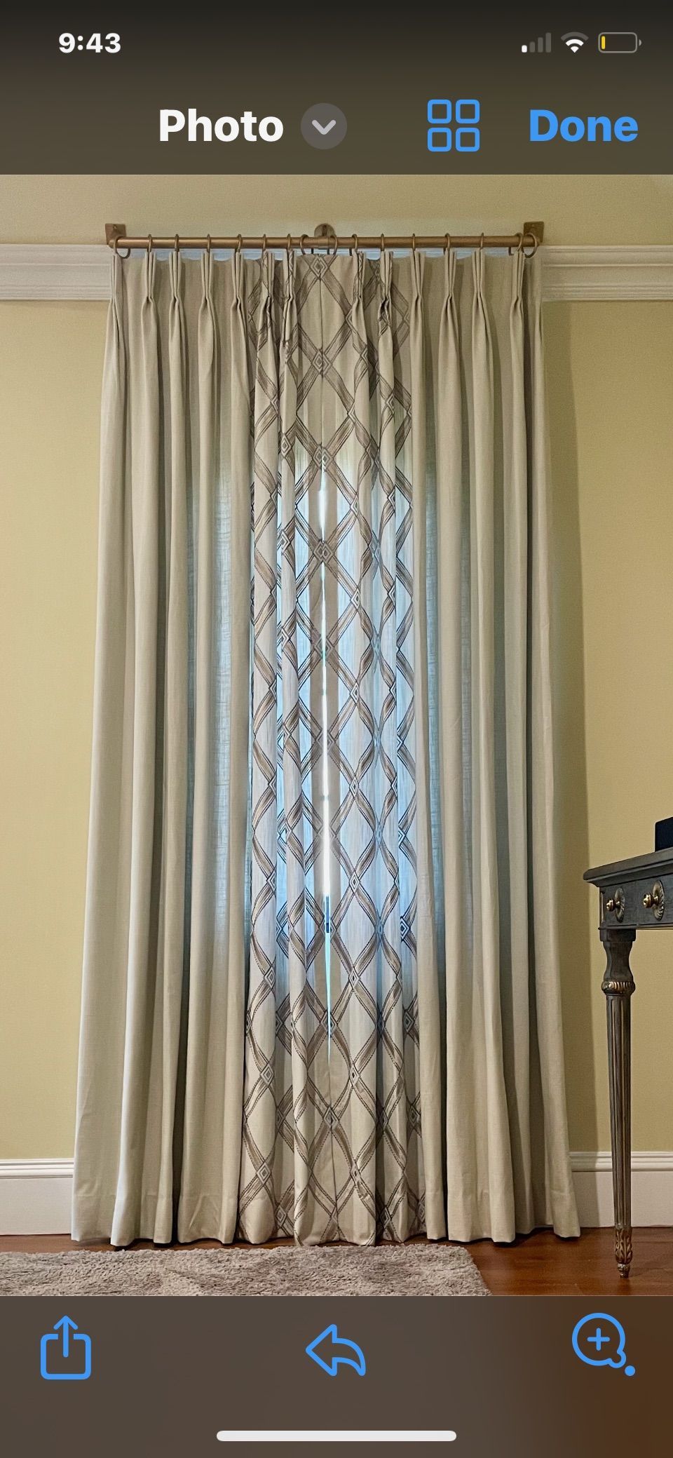 Beige curtains with embroidered center panel hang in a room.