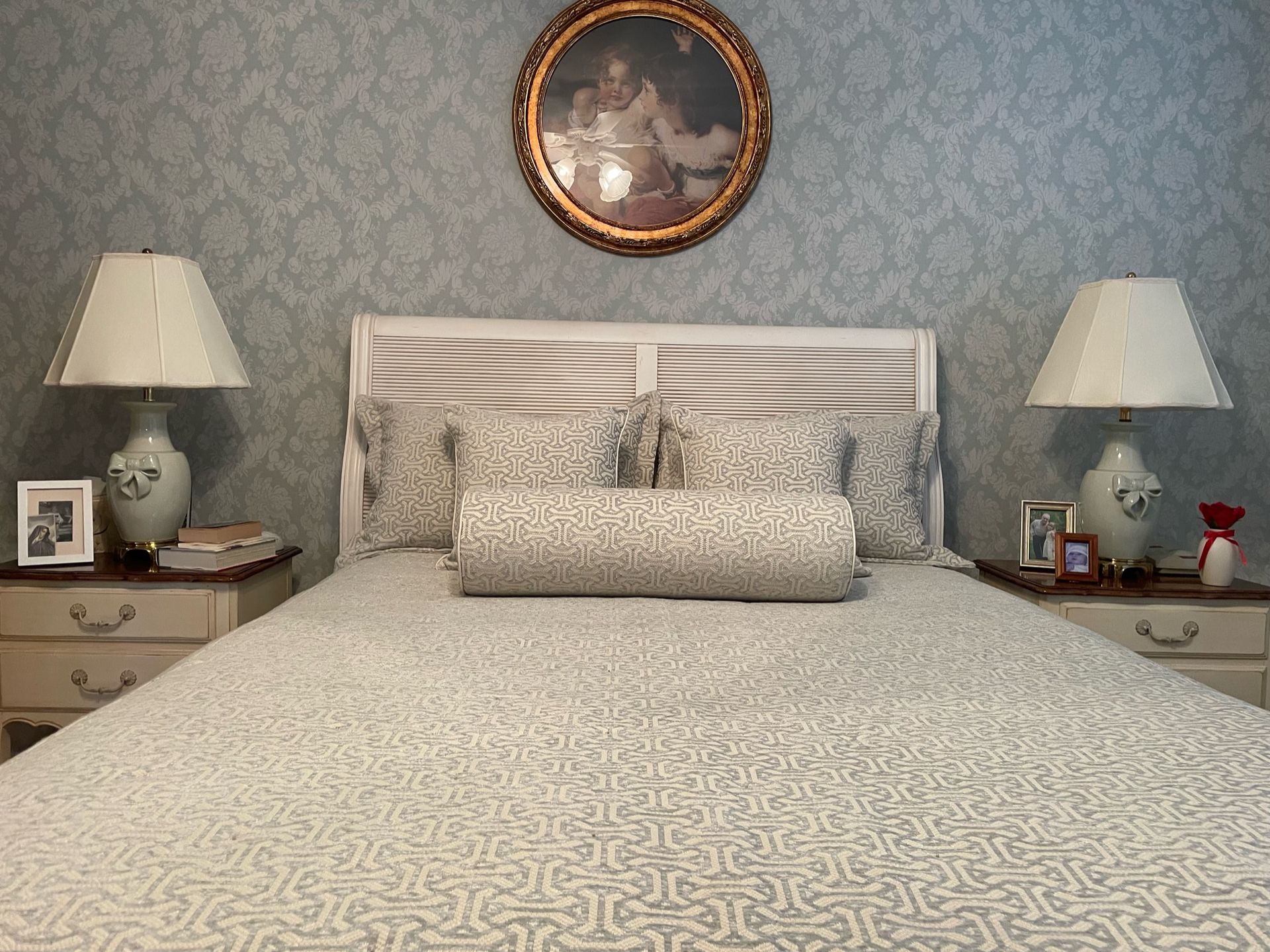 Bedroom with a bed centered, nightstands with lamps on either side, and artwork above the headboard.