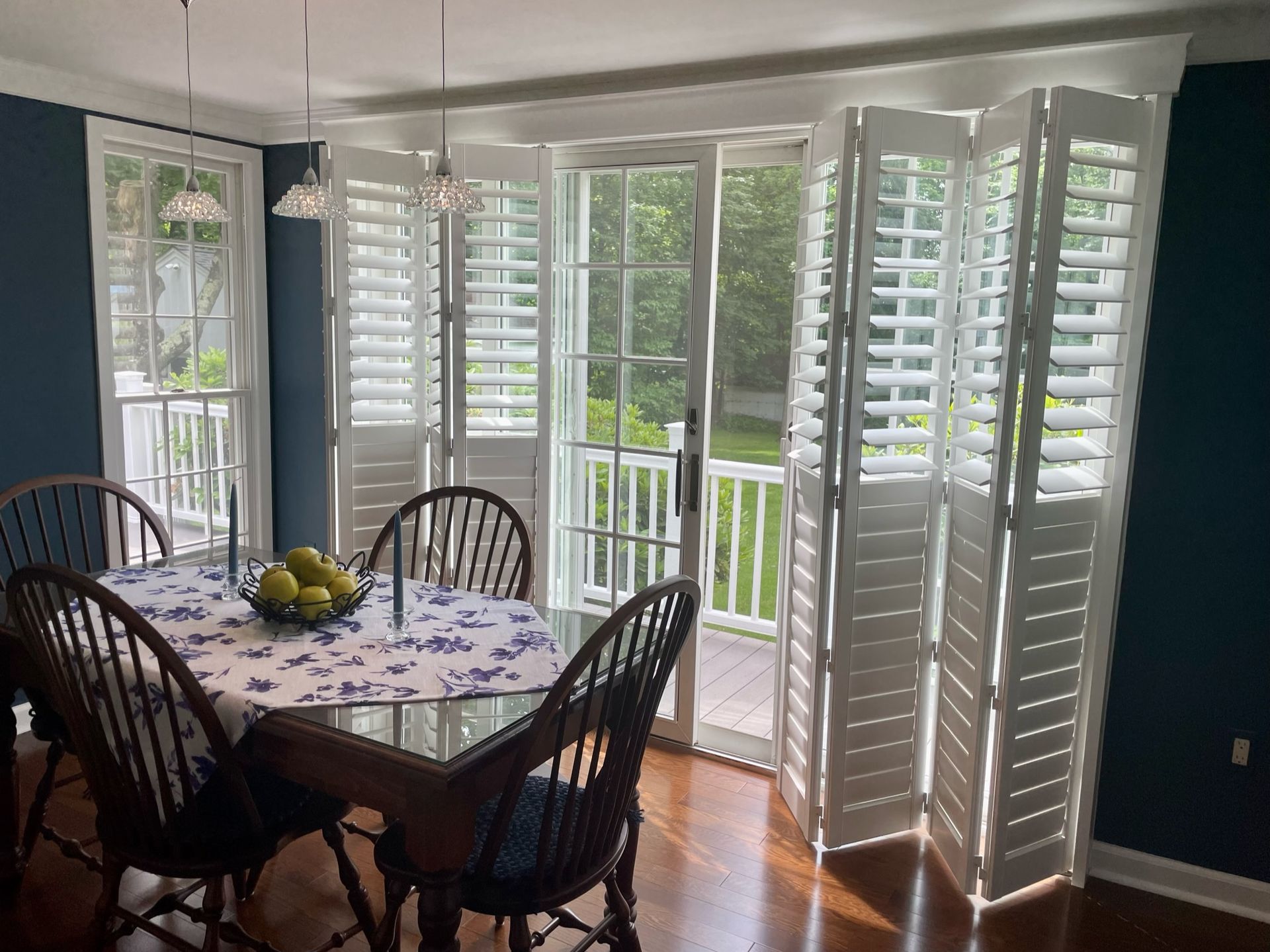 Dining room with a table set for four, shutters on windows and door.