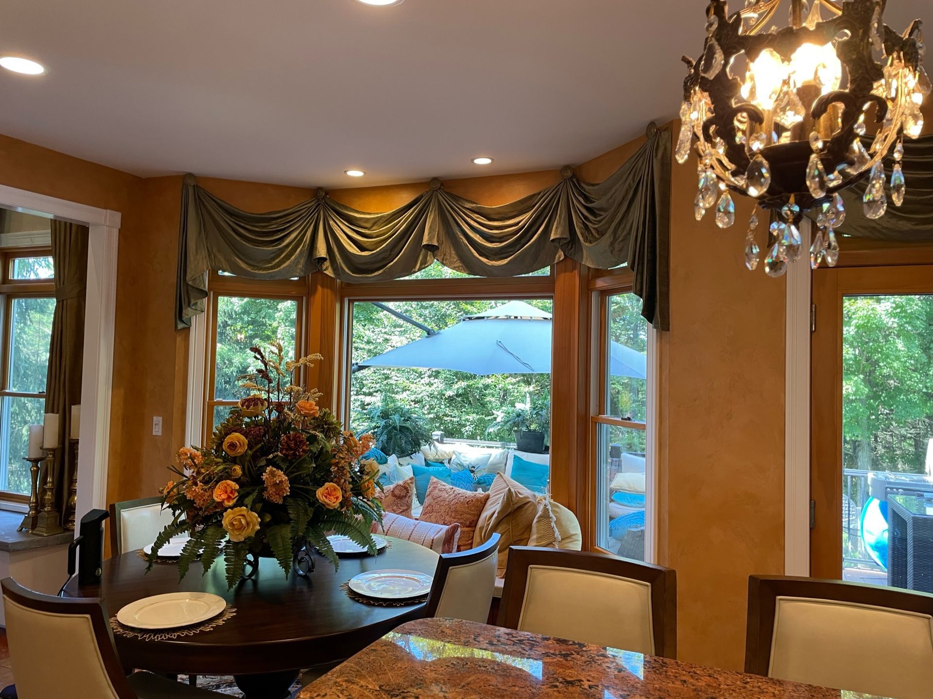 Dining room with dark wooden table, flowers, and a view of a patio with an umbrella.