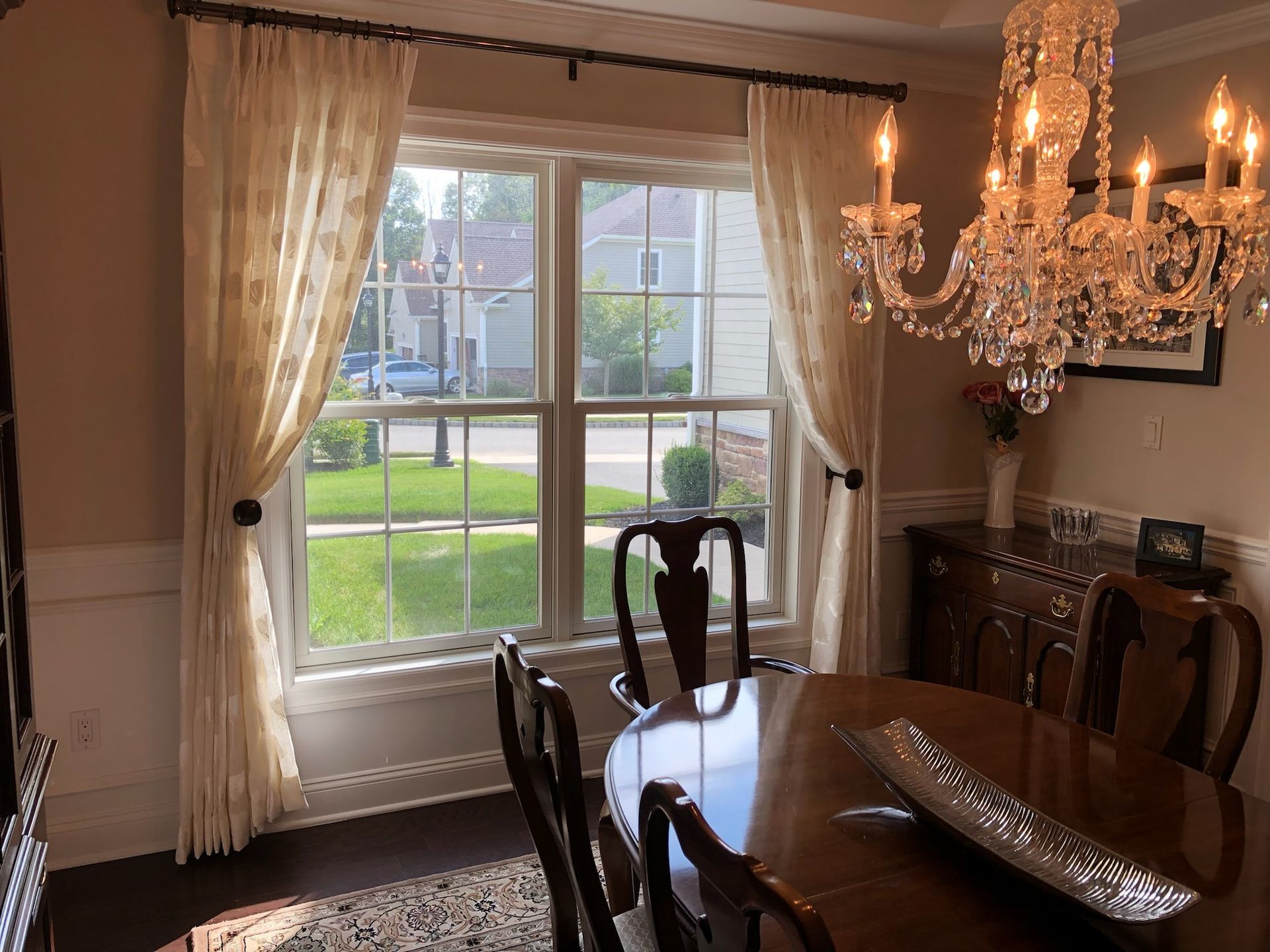 Dining room with a window, sheer curtains, chandelier, and table.