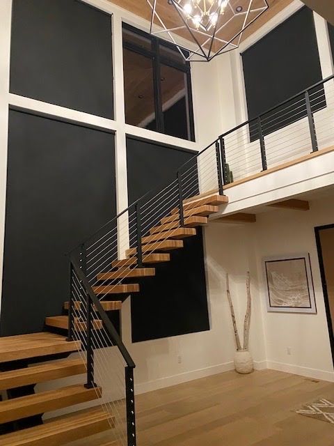 Modern interior with wood staircase, black wall, and a geometric chandelier.