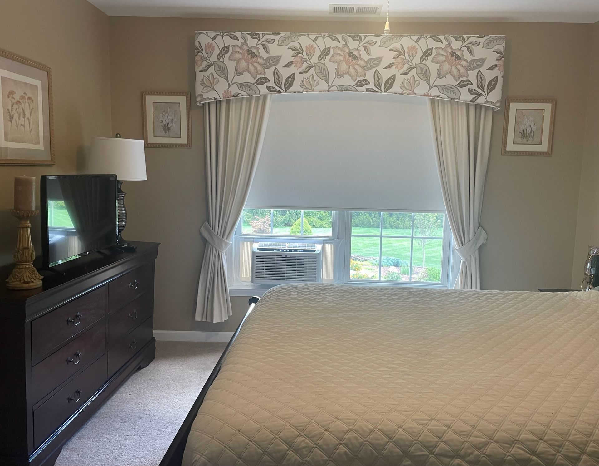 Bedroom with a bed, dresser, window with floral valance, and curtains.