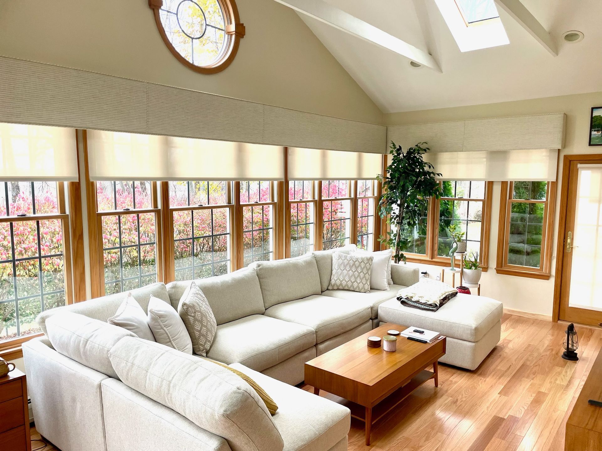 Spacious living room with a large sectional sofa, coffee table, and tall windows overlooking greenery.