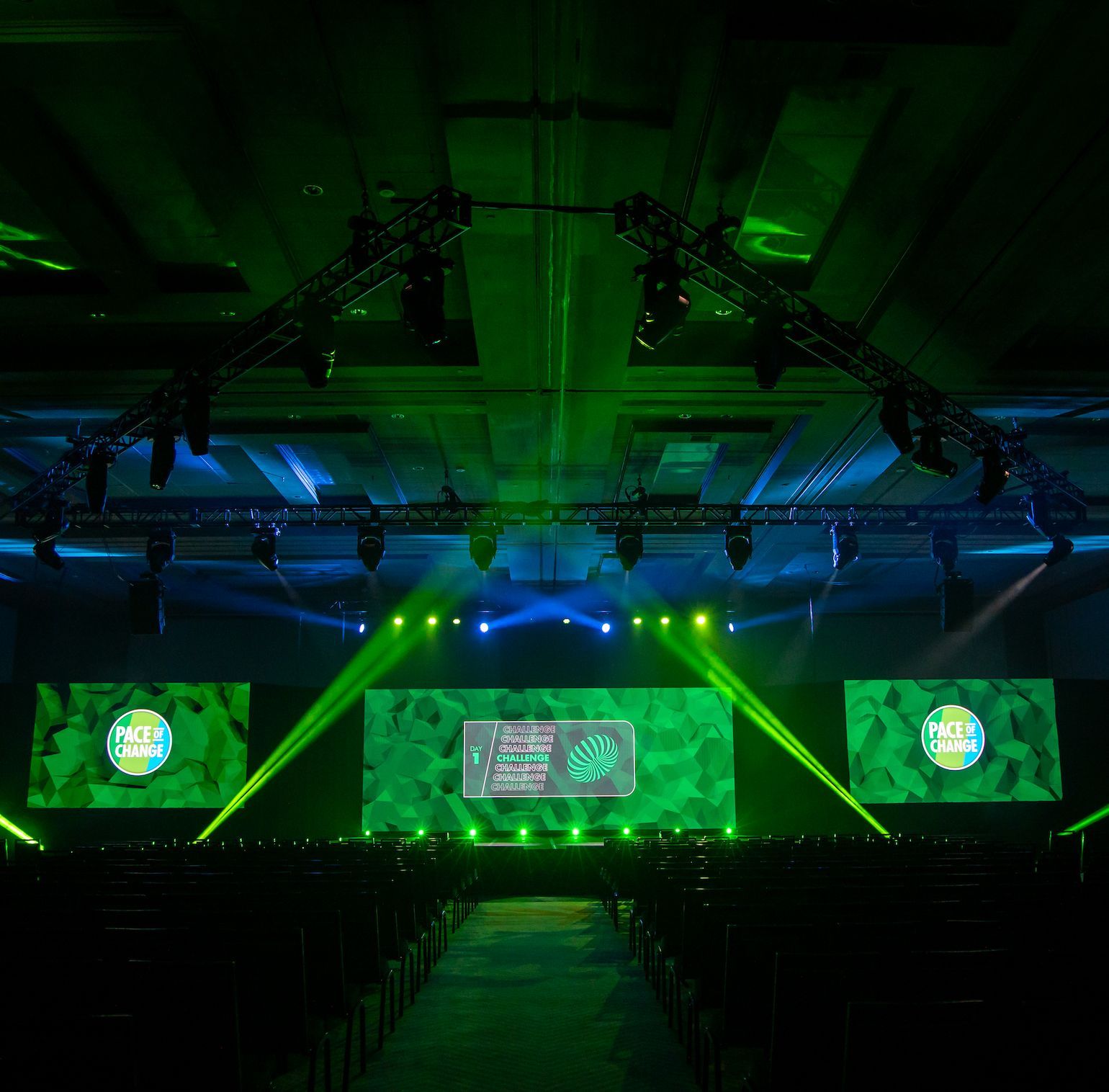 Custom stage lighting and LED video displays transforming a corporate conference general session.