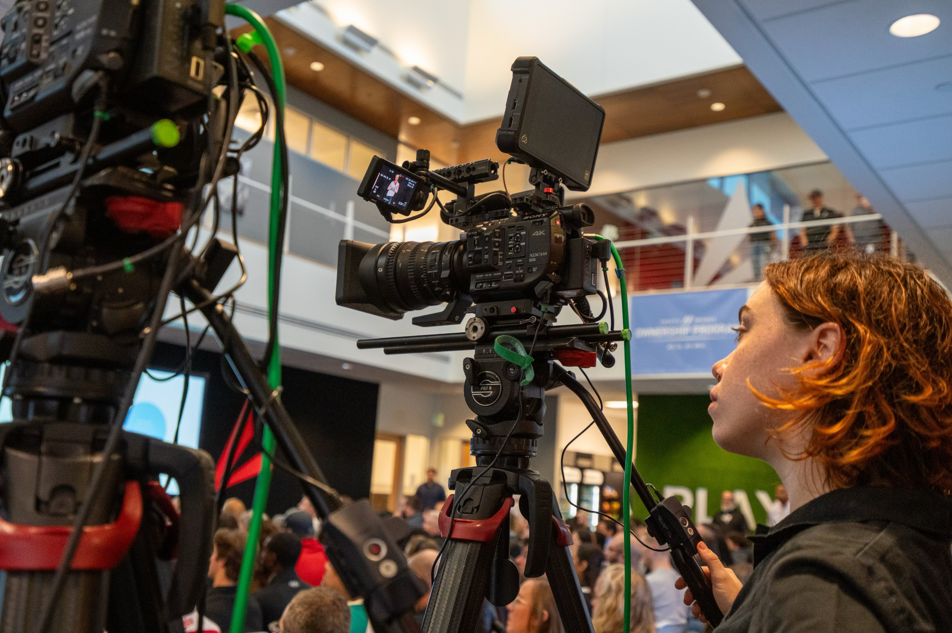 Broadcast camera operator capturing a multi-camera live stream during a corporate conference.