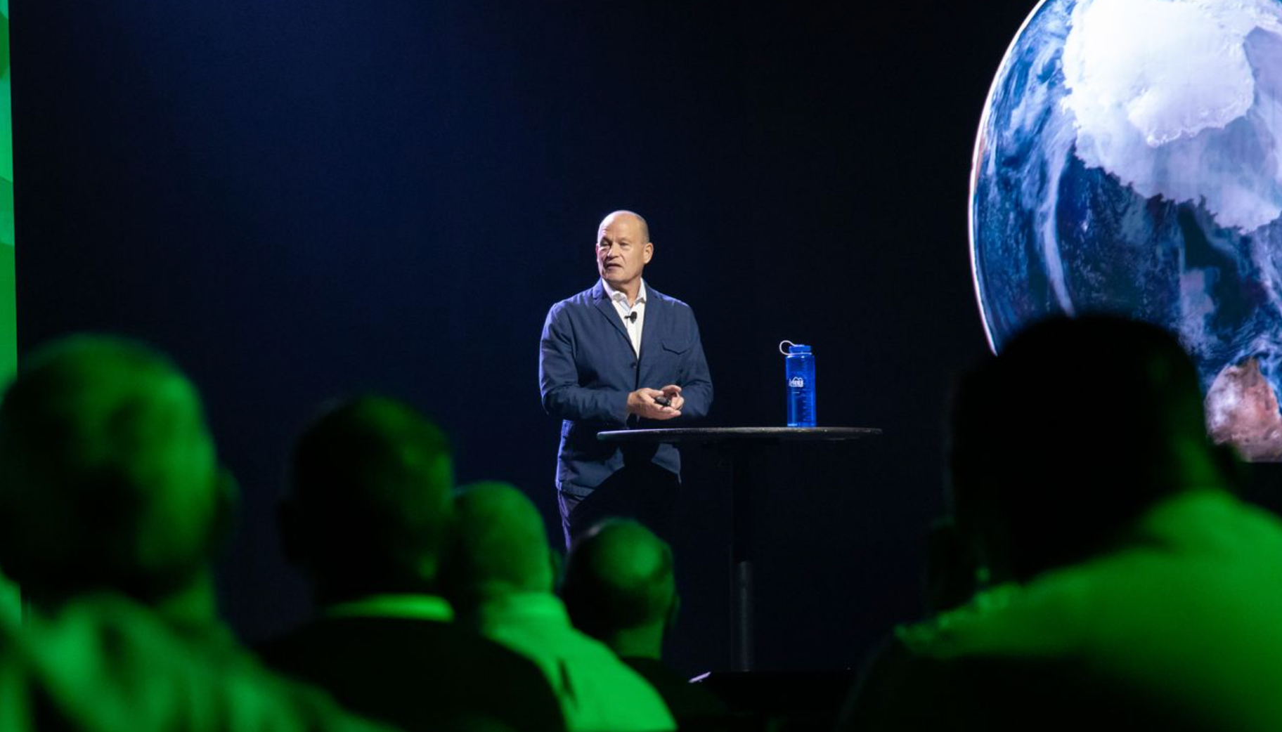 Corporate live event production with a presenter on stage and large-format video display.