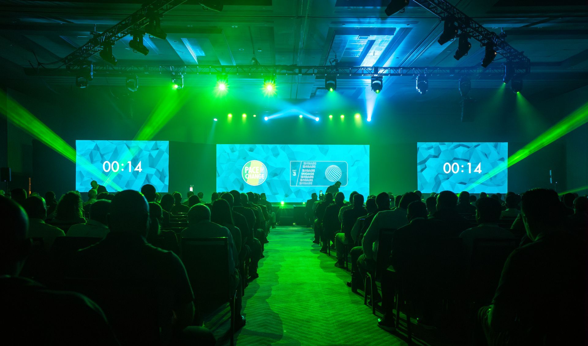 Audience gathered for a corporate conference featuring immersive stage lighting and large-format LED presentation displays.