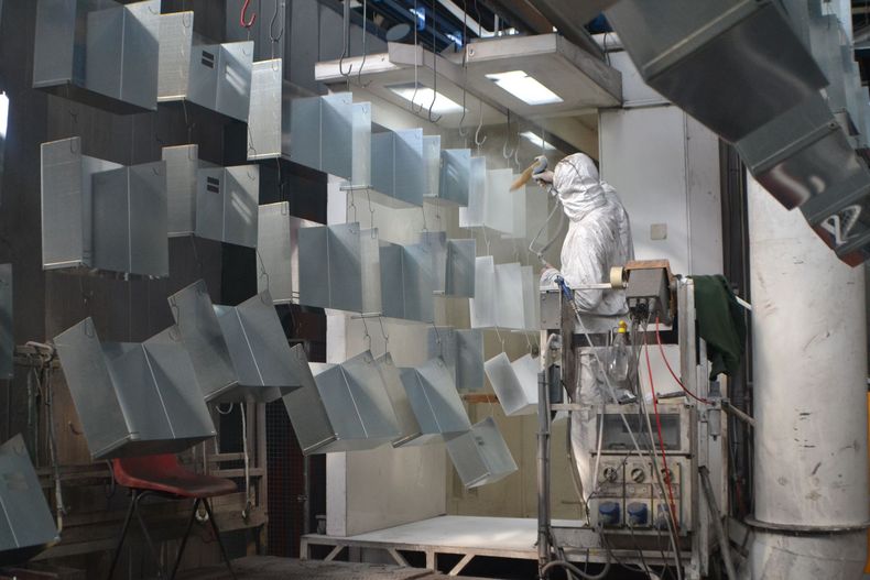 Un uomo con una tuta protettiva sta lavorando su una macchina in una fabbrica.