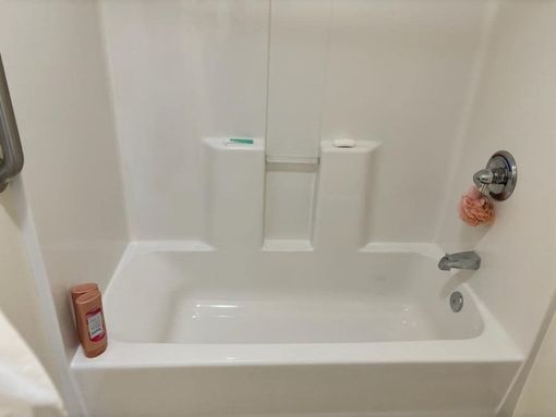 White bathtub and shower surround with toiletries.