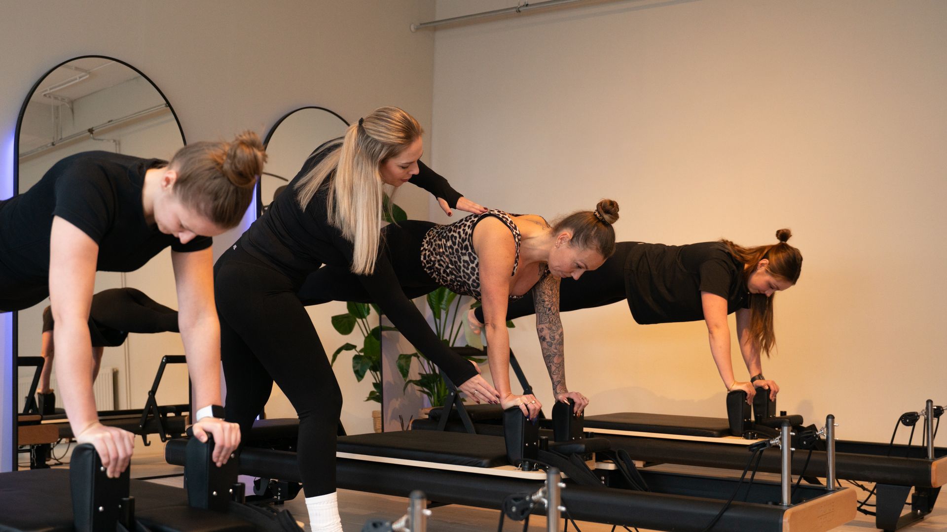 Een personal trainer helpt een vrouw op een reformer pilates bank.