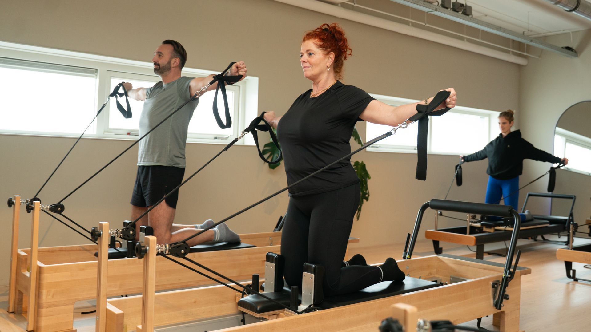 Een vrouw en een man doen mee aan een reformer pilates les.