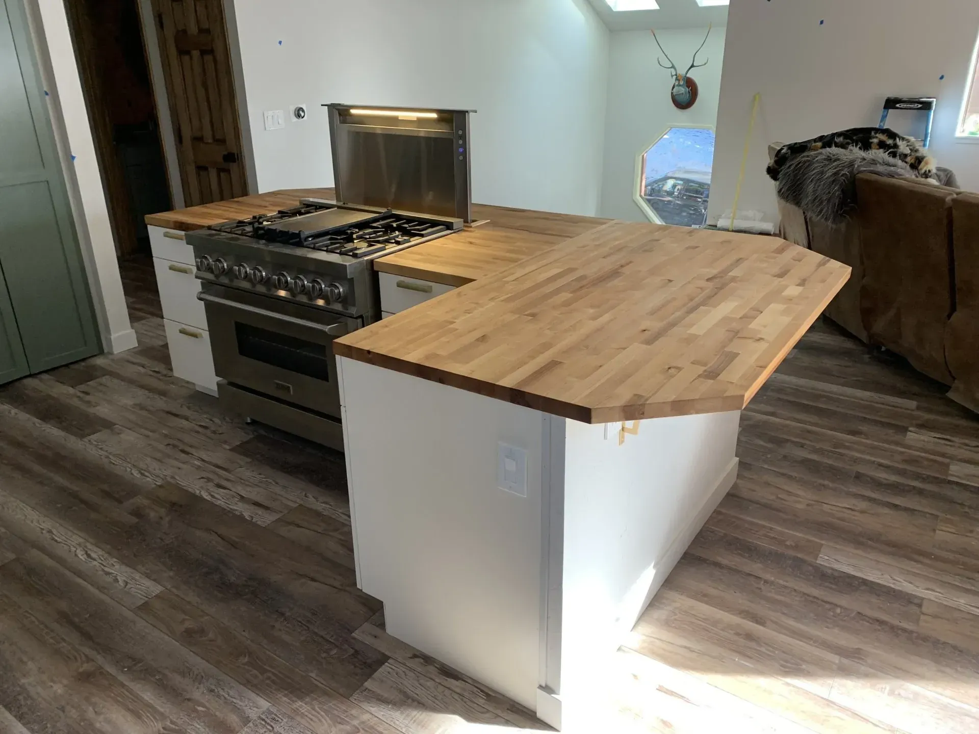 Kitchen with a stainless steel stove and a wooden island countertop on a dark wood floor.