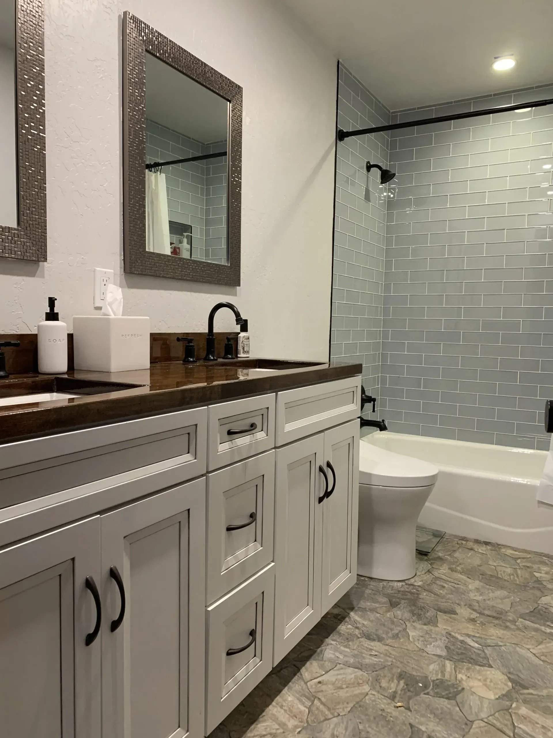 Bathroom with white vanity, wood countertop, mirror, tub, and glass shower tile wall