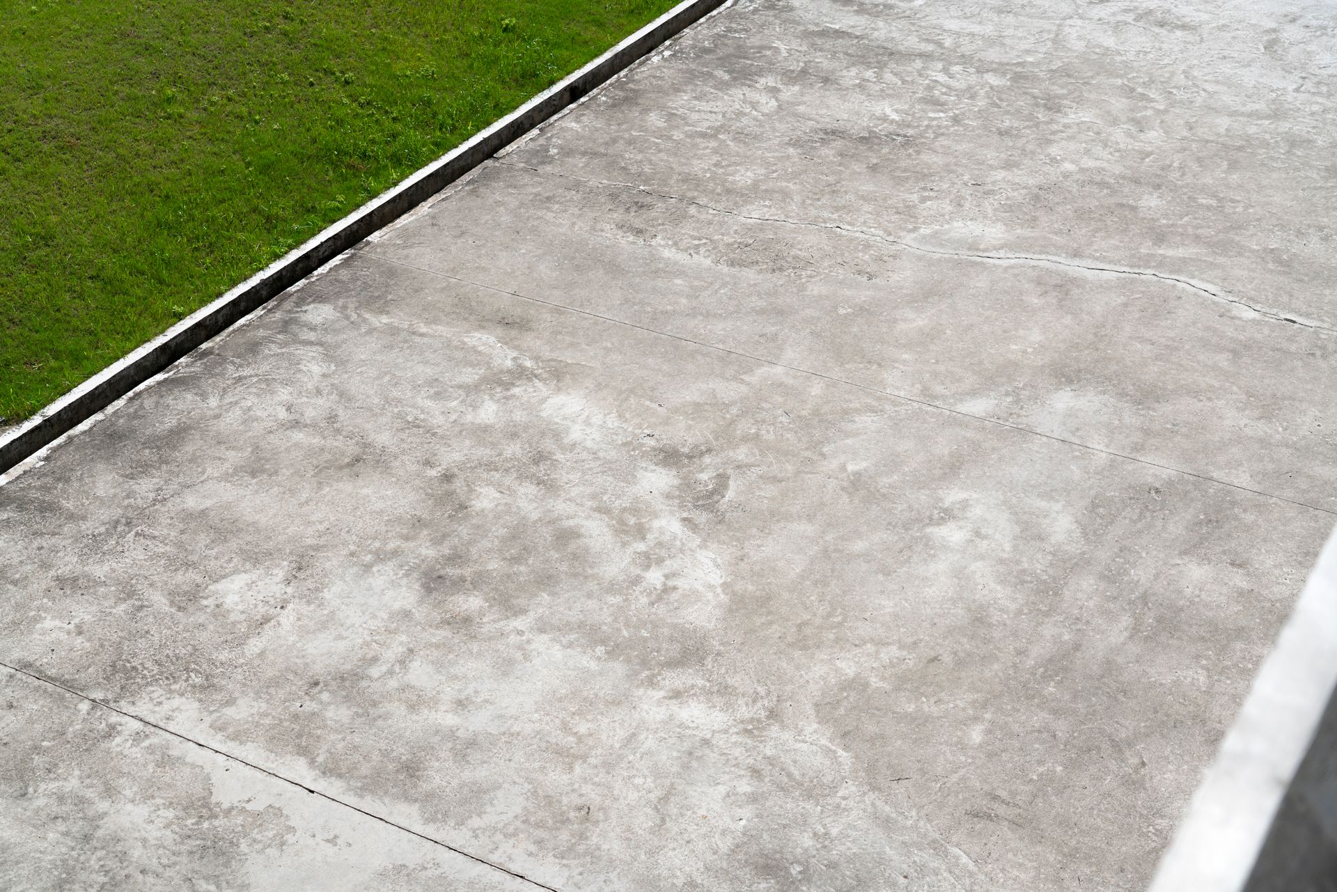 A concrete walkway leading to a grassy field.