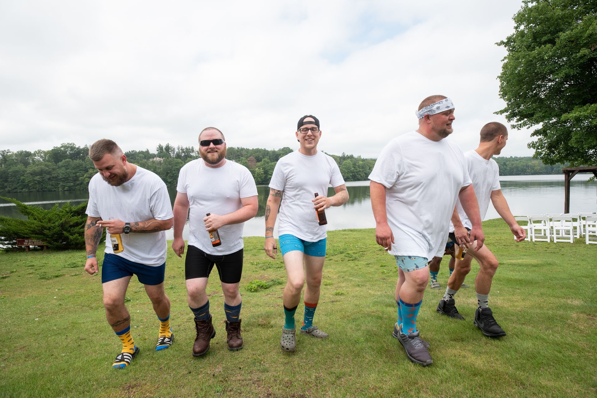 A photo with a group of groomsmen are walking on a lush green field taken by Ever After Studio.